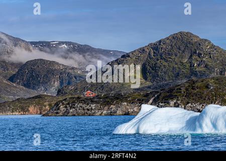 Casa rossa solitaria tra montagne e iceberg vicino a Rodebay, villaggio di Kitaa, Groenlandia Foto Stock