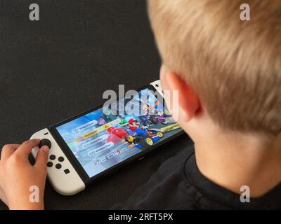 Ragazzo che gioca a Mario Kart su una nuova console Nintendo Switch in modalità portatile. Immagine ravvicinata sulle mani. Copenhagen, Danimarca - 5 agosto 2023. Foto Stock