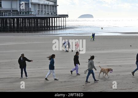 Weston Super Mare, Regno Unito. 5 agosto 2023. In un pomeriggio ventoso e caldo, la gente è vista fare una passeggiata sulla spiaggia presso il famosissimo Molo Weston. Foto: Robert Timoney/Alamy Live News Foto Stock