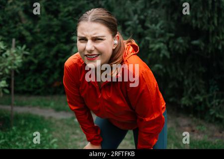 Donna con corpo extra-size che si rilassa dopo una sessione di allenamento all'aperto. Donna in abbigliamento sportivo che si prende una pausa dall'esercizio fisico. Foto Stock