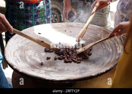 Fagioli di cacao crudi arrostiti su una tradizionale griglia di argilla comal in Guatemala per la preparazione del cioccolato Foto Stock