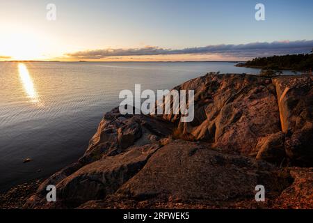 Splendida vista sulla costa rocciosa e la scogliera e sul Mar Baltico a Hanko, Finlandia, al tramonto in estate. Foto Stock