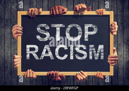 Molta mano tiene in mano uno striscione con il testo " Stop razzismo" su sfondo scuro Foto Stock