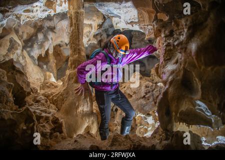 Giovane donna che si tuffa in una caverna. Concetto di femminismo. Concetto di sport femminile. Foto Stock