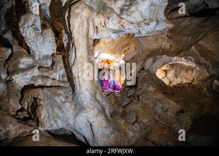 Giovane donna che si tuffa in una caverna. Concetto di femminismo. Concetto di sport femminile. Foto Stock