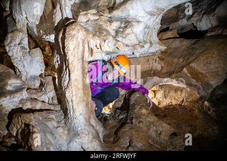 Giovane donna che si tuffa in una caverna. Concetto di femminismo. Concetto di sport femminile. Foto Stock