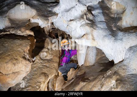 Giovane donna che si tuffa in una caverna. Concetto di femminismo. Concetto di sport femminile. Foto Stock