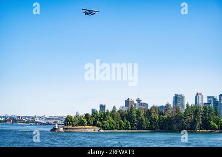 A seaplane soars over Brockton Point in Vancouver's Stanley Park, Vancouver, BC, Canada.  Cruise ship and city skyline are visible. Stock Photo