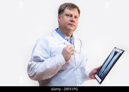 Un medico maschio un cappotto bianco con una radiografia in mano, sfondo bianco. Foto Stock