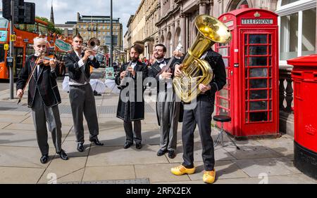 St Andrew Square, Edimburgo, Scozia, Regno Unito, 06 agosto 2023. Schërzo al Festival Fringe di Edimburgo: La commedia musicale slapstick torna al Fringe. Nella foto: Gli artisti suonano un pezzo improvvisato con strumenti di ottone. Crediti: Sally Anderson/Alamy Live News Foto Stock