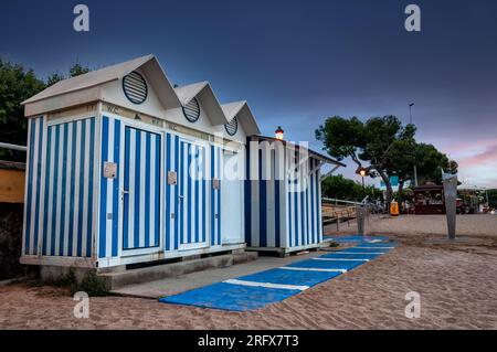 Bagno pubblico e cabina con strisce blu e bianche sulla spiaggia Foto Stock