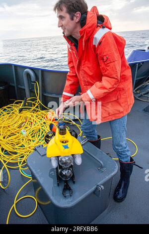 Scienziato marittimo che prepara un mini-Rov sottomarino in miniatura azionato a distanza. Foto Stock