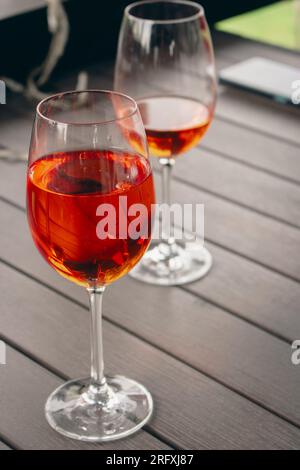 Due bicchieri di cocktail Aperol Spritz. Occhiali da vista con vino rosato. Bar all'aperto. Tavolo del caffè sul marciapiede. Festa con alcol. Cocktail all'arancia. Foto Stock