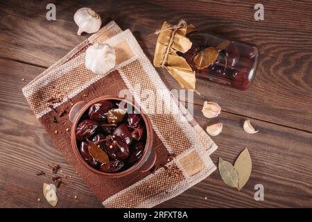 Prugne marinate con spezie in vaso di vetro sul tavolo da cucina Foto Stock