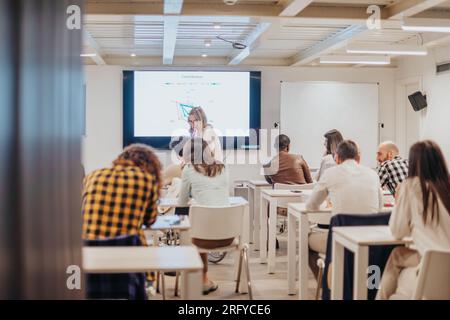 Coach di mezza età che insegna economia con il suo assistente maschile disabile in sedia a rotelle Foto Stock