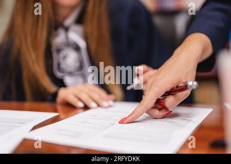 Primo piano di una donna che guida la ragazza dove scrivere sul foglio di carta Foto Stock