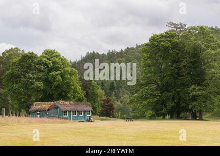 Un visitatore seduto su una panchina all'esterno del padiglione dei Cricket di paglia nel terreno del Castello di Balmoral sul Royal Deeside Foto Stock