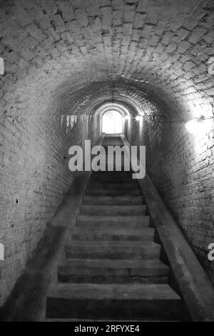 Foto monocromatica di scale in pietra all'interno di un tunnel al forte Drop Redoubt, dover, Inghilterra. Foto Stock