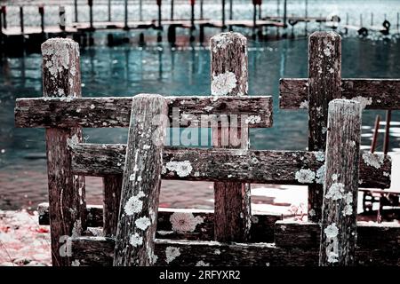 Vecchia recinzione in legno fatiscente sul molo vicino alla riva del lago Foto Stock