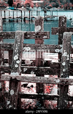 Vecchia recinzione in legno fatiscente sul molo vicino alla riva del lago Foto Stock