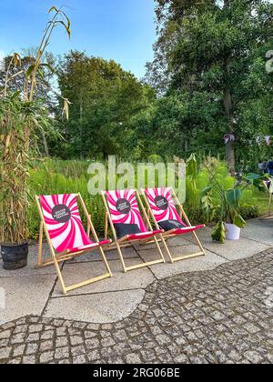 BERLINO, GERMANIA - 22 LUGLIO 2023: Lettini e ombrelloni con il logo del KULTUR SOMMER FESTIVAL nel Britzer Garten. Foto Stock