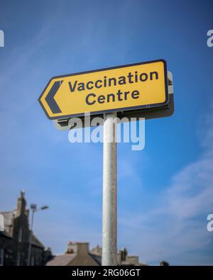 Immagine di un segno giallo di vaccinazione contro il coronavirus covid-19 su sfondo blu. Foto scattata a Fraserburgh, nel nord-est della Scozia. Foto Stock