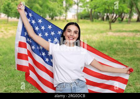 4 luglio - giorno dell'indipendenza dell'America. Donna felice con la bandiera nazionale degli Stati Uniti nel parco Foto Stock