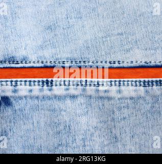 Bordi in denim blu con cuciture e cotone arancione. Tessuto jeans color blu chiaro e arancione. Spazio di copia per il testo Foto Stock