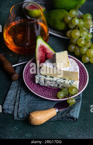 Spuntini squisiti assortiti con formaggio e serviti su un piatto con uva, fichi e bevande Foto Stock