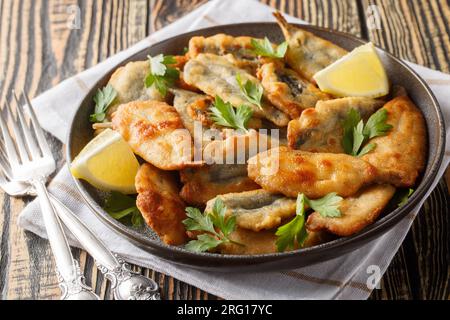 Piatto di acciughe fritte con primo piano al limone sul tavolo. Orizzontale Foto Stock