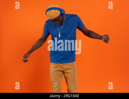 Concentrato di giovani uomini afroamericani in berretto con gli occhi chiusi mentre si stende con la testa ad arco e si ascolta la musica intensamente con Th Foto Stock