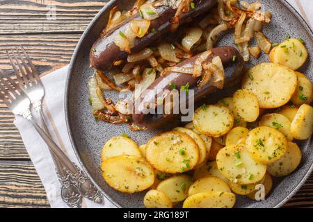 Budino nero fatto in casa con cipolle fritte con contorno di patate da vicino su un piatto sul tavolo. Vista superiore orizzontale dall'alto Foto Stock