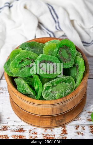 Fette di kiwi essiccate in un recipiente di legno. Fette di kiwi naturali essiccate al sole su sfondo di legno bianco Foto Stock