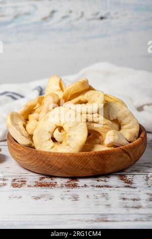 Fette di mela essiccate in un recipiente di legno. Fette di mela naturale essiccate al sole su fondo di legno bianco. primo piano Foto Stock