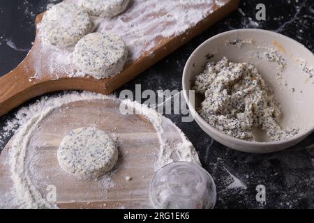 foto della preparazione di cheesecake con semi di papavero, tavole di legno, impasto di formaggio cottage, semi di papavero, uova, farina, sul tavolo Foto Stock