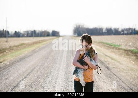 Ragazzo che tiene il suo cane mentre esplora una strada sterrata. Foto Stock