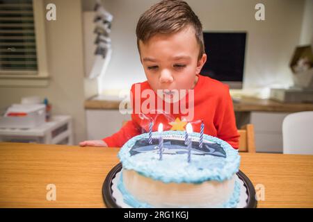 il bambino di sei anni fa sputare le candele sulla sua torta di squalo Foto Stock