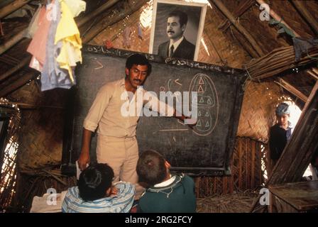 Marsh Arabs, Iraq meridionale. Marsh Arab Children a scuola, un edificio tradizionale costruito in canne. Ritratto di Saddam Hussein appeso al muro. Hammar palude l'Iraq degli anni '1984 1980 HOMER SYKES Foto Stock