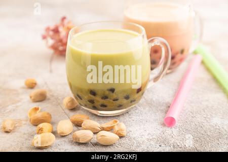 Tè bollente con pistacchio e caramello in vetro su fondo marrone in cemento. Concetto di bevanda salutare. Vista laterale, primo piano, messa a fuoco selettiva. Foto Stock
