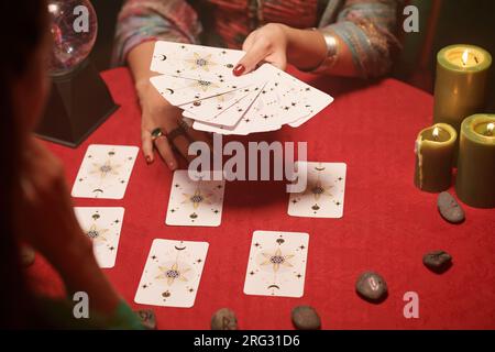 Mani di veggente che chiedono a donna di scegliere le carte da spargere Foto Stock