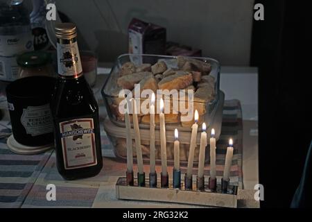 Menorah illuminata e una bottiglia di vino Manischewitz su un tavolo durante Hannukah Foto Stock