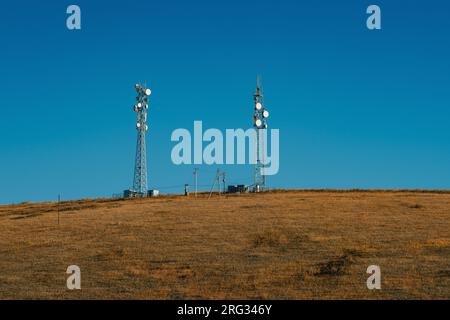 Torre di telecomunicazione con molte antenne diverse sulla collina Foto Stock