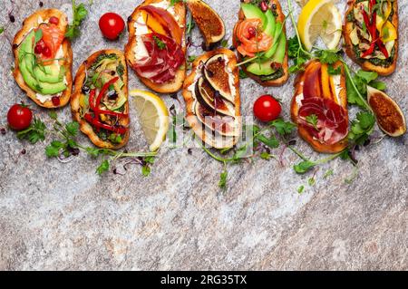 Set di bruschette assortite con vari condimenti per le vacanze sulla tavola di pietra. Vista dall'alto. Concetto di cibo per feste. Foto Stock