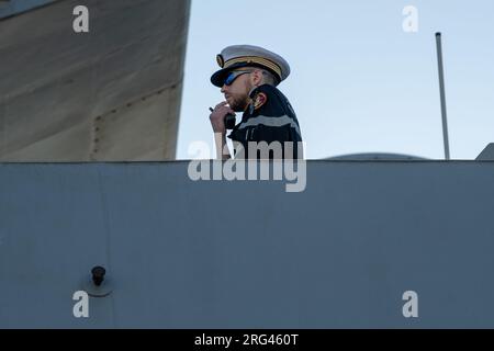 Tolone, Francia. 2 agosto 2023. L'ufficiale di marina osserva le manovre della fregata multimissione LORRAINE nel porto militare di Tolone durante l'attracco. La fregata multimissione con capacità di difesa aerea rafforzata (FREMM-da) Lorraine sta tornando al porto di Tolone dopo una missione della durata di più di quattro mesi, principalmente nell'area Indo-Pacifico. Il 24 e 25 aprile, la fregata prese parte all'operazione Sagitaire, che permise l'evacuazione dal Sudan di quasi 400 persone di circa sessanta nazionalità diverse a seguito dello scoppio degli scontri tra l'esercito sudanese e il gruppo paramilitare Foto Stock