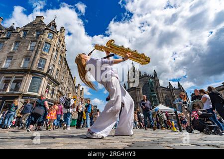 Edimburgo, Scozia, Regno Unito. 7 agosto 2023. Molti attori che promuovono i loro spettacoli e artisti di strada intrattenono il pubblico sul Royal Mile il secondo giorno del festival Edinburgh Fringe. PIC; Louisa Roberts suona il sax baritono sul Royal Mile. È membro della Macready Theatre Young Actors Company che sta eseguendo il 2nd Picture of Dorian Gray by Vote Garriga al C Venues Aquila durante il Fringe. Iain Masterton/Alamy Live News Foto Stock