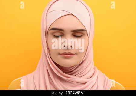 Ritratto di donna musulmana in hijab su sfondo arancione Foto Stock