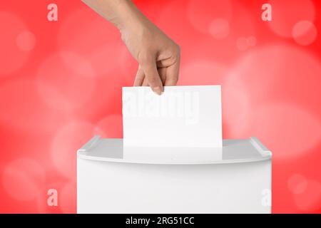 Uomo che mette il suo voto nelle urne su sfondo rosso, primo piano Foto Stock