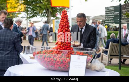 Fragole e crema gratuite regalate agli appassionati di corse durante il Qatar Goodwood Festival Meeting 2023 all'ippodromo di Goodwood, Chichester Foto Stock