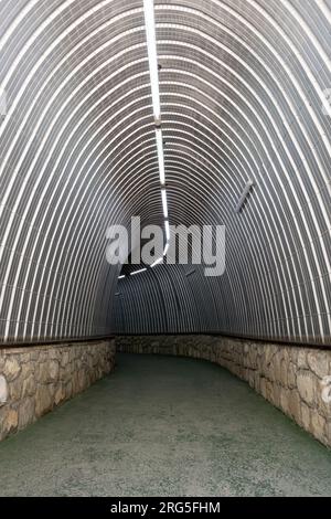 Tunnel rivestito con lastre di metallo ondulato che conducono alla montagna per accedere alla funicolare nel parco nazionale Picos da Europa in Spagna Foto Stock