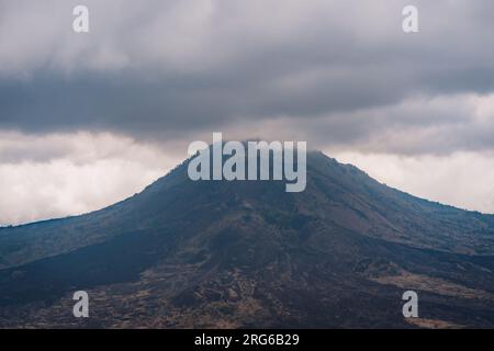 Vista panoramica della cima del monte Batur tra le nuvole. Misteriosa nebbia mattutina al vulcano Batur Foto Stock